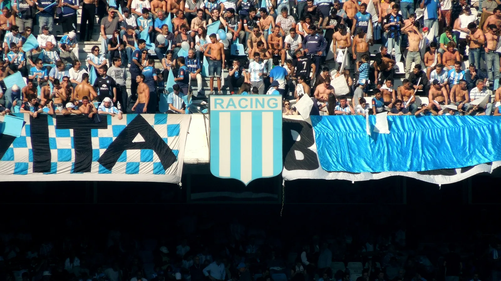 Argentina supporters waving the light-blue and white flag inside a packed World Cup stadium — Lionel Messi opens Argentina's World Cup 2026 campaign at Arrowhead Stadium in Kansas City against Algeria on June 16