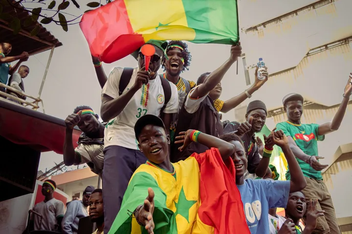 African football fans waving national flags, evoking the continent-wide stakes of WAFCON 2026 and the qualifying race for the 2027 Women's World Cup